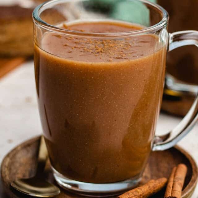 Atole finished in cup on brown plate, cinnamon sticks on plate 4x3