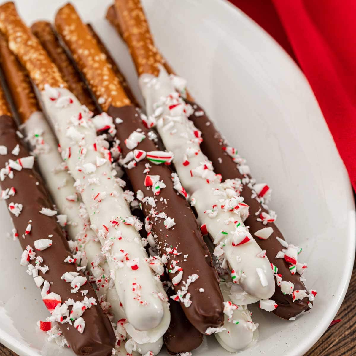 Peppermint Bark Pretzels dipped in chocolate and covered in candy cane pieces on plate