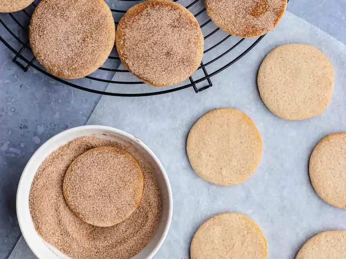 Cookies being dipped in cinnamon sugar mixture.