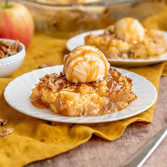 Apple Dump Cake slice on plate with scoop of ice cream and caramel drizzle