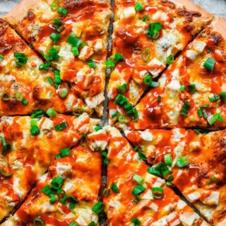 Large chicken and cheese pizza on serving dish.