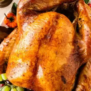 Whole turkey glazed with butter on a bed of vegetables