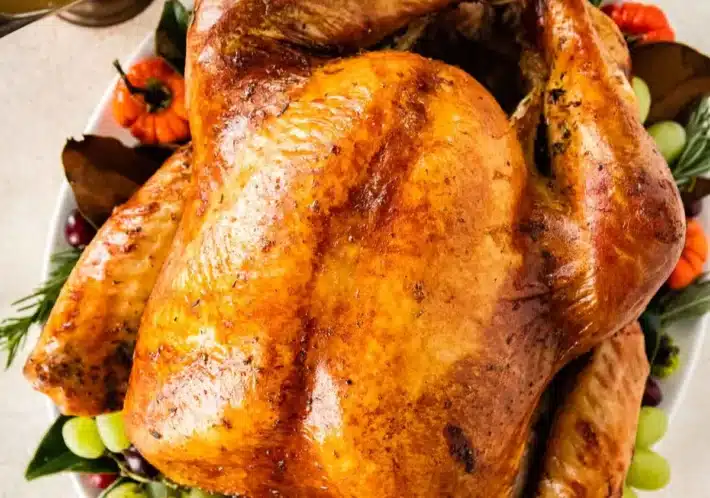 Whole turkey glazed with butter on a bed of vegetables