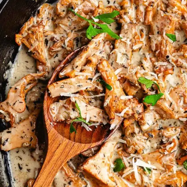 Mushrooms in a creamy wine sauce with serving spoon.