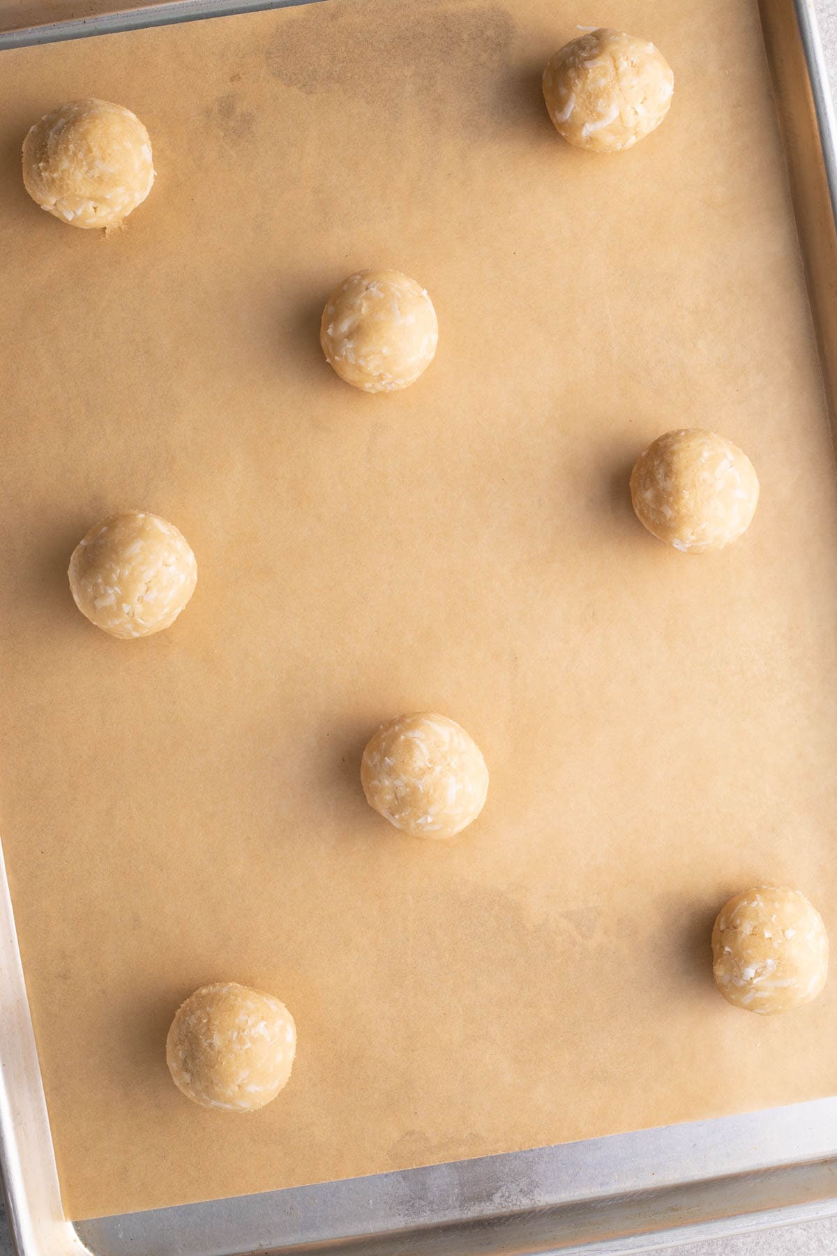 Coconut Cookies balls of dough on parchment lined cookie sheet