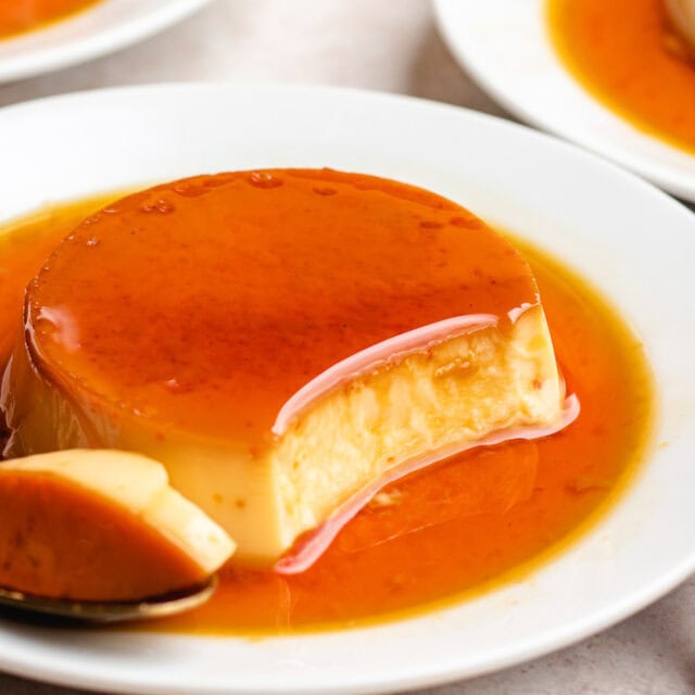 Plate of creme caramel with glossy caramel and a spoon.