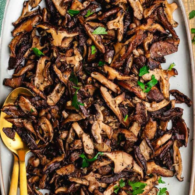 Cooked mushrooms on serving plate with spoon.