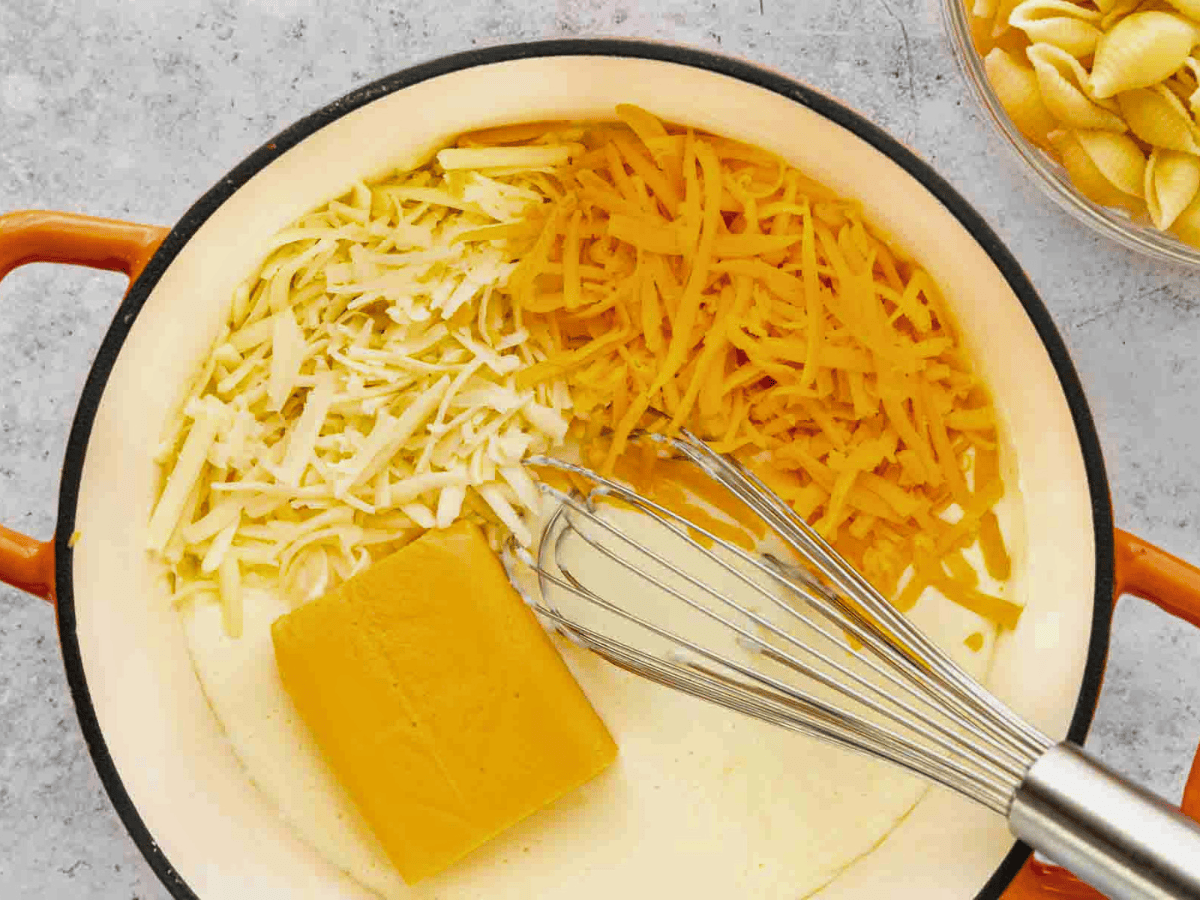 Cheeses and milk in pot with whisk