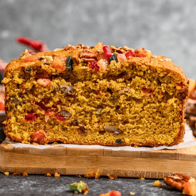 Slice of Fruitcake from the side exposing all the bits of candied fruit and pumpkin.