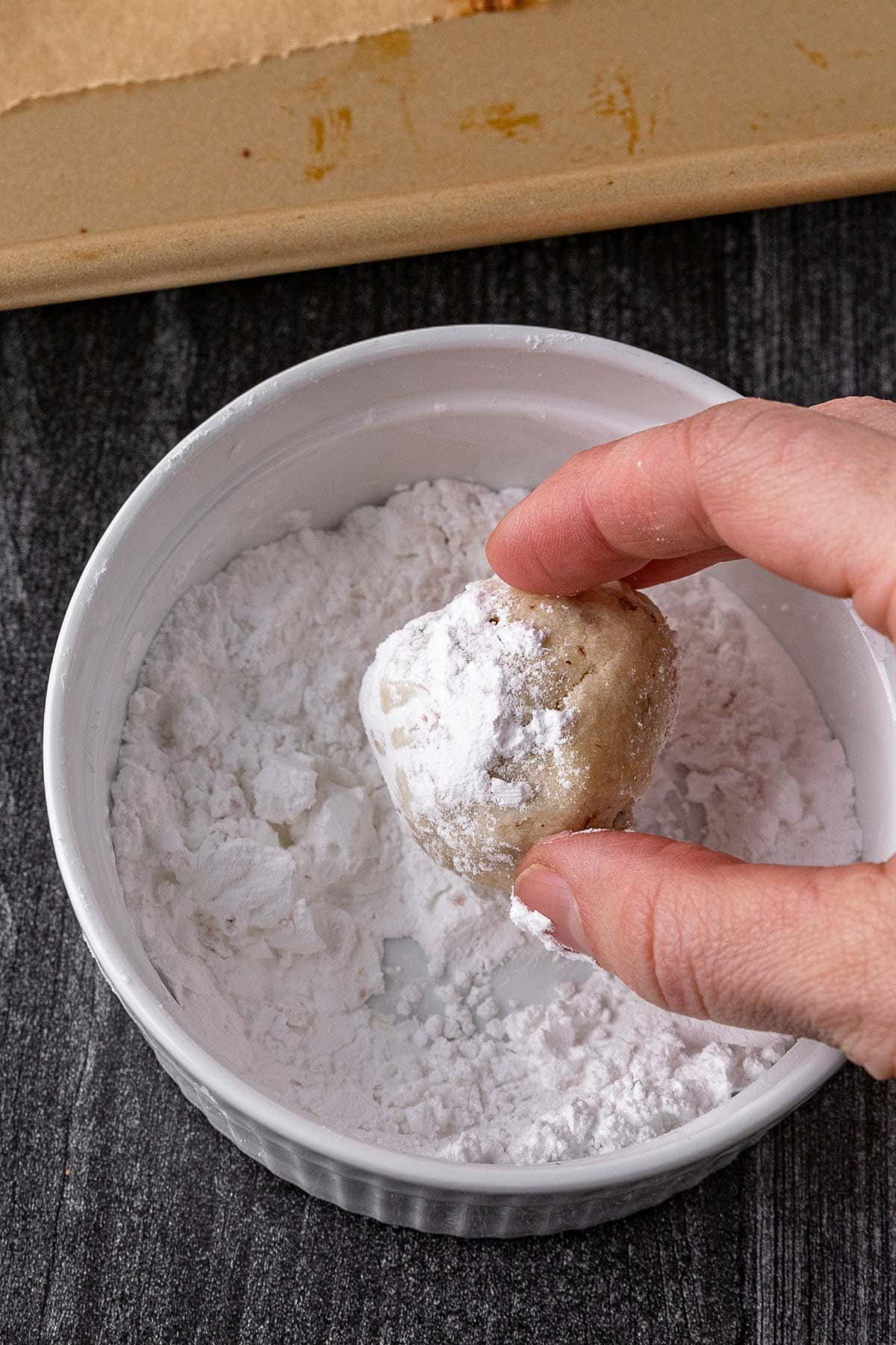 Snowman Snowball Cookies rolling cookie in powdered sugar