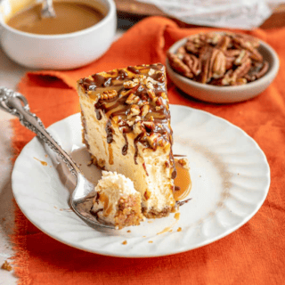 Slice of caramel and chocolate topped cheesecake on plate and bite on fork