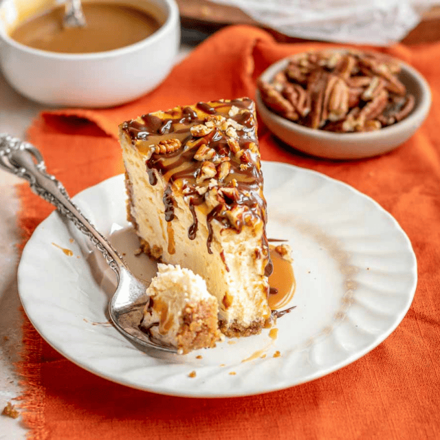Slice of caramel and chocolate topped cheesecake on plate and bite on fork
