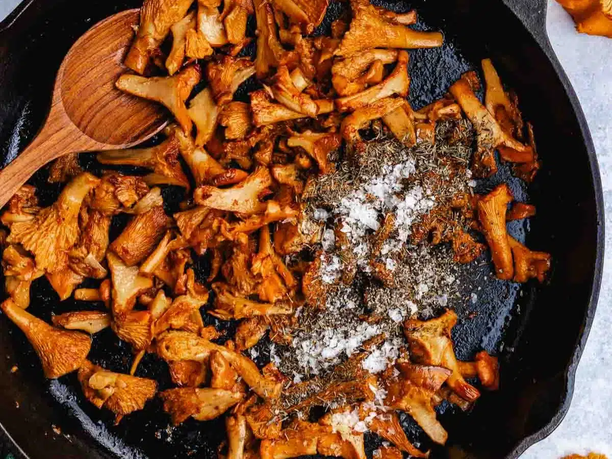 Mushrooms sautéing in pan with salt and pepper.