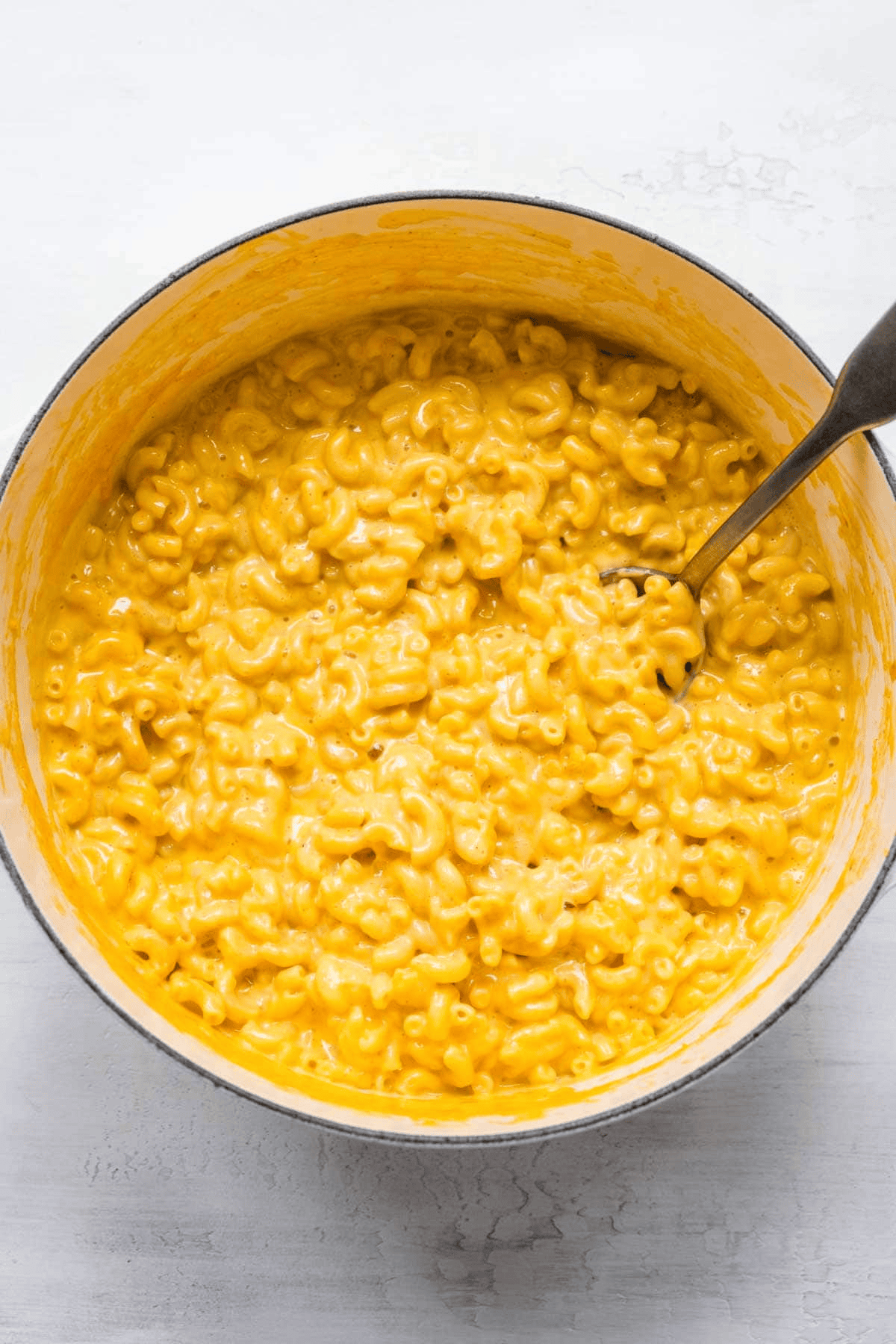 Finished macaroni and cheese in a pot with a spoon