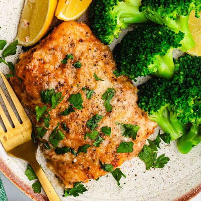 Fish filet with broccoli on dinner plate.