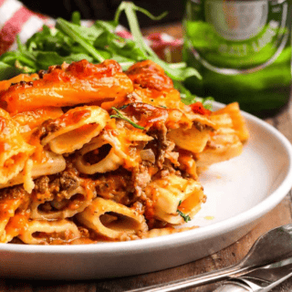plated ziti on a table with beer in the back