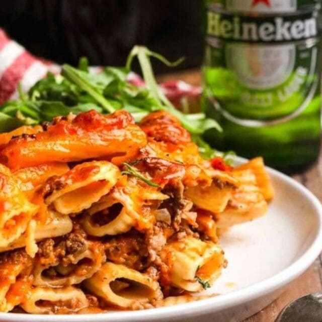 Ziti on a white plate with a beer.