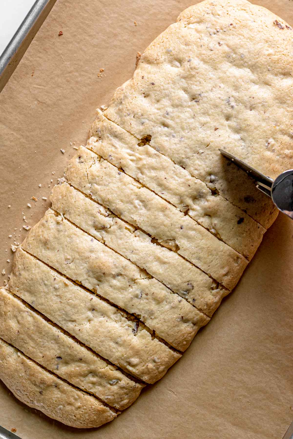 Chocolate Hazelnut Biscotti slicing semi baked dough log with pizza cutter