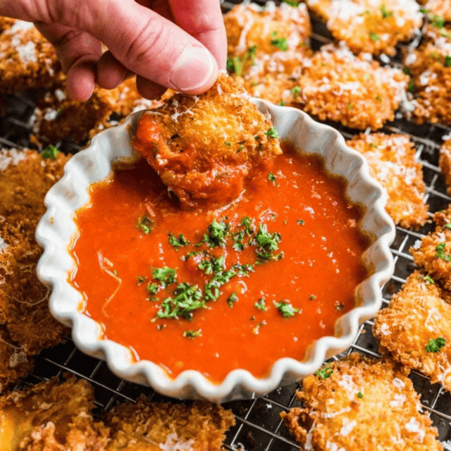 ravioli being dipped into red sauce