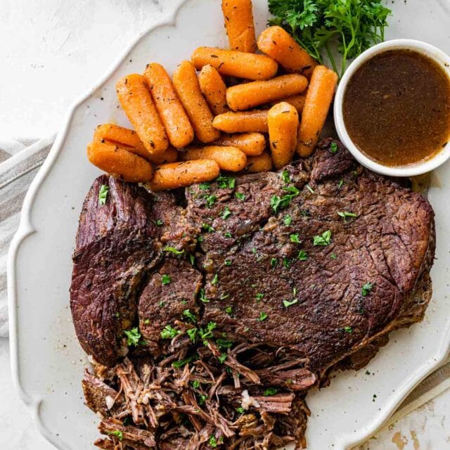 cooked beef roast and carrots on a white plate