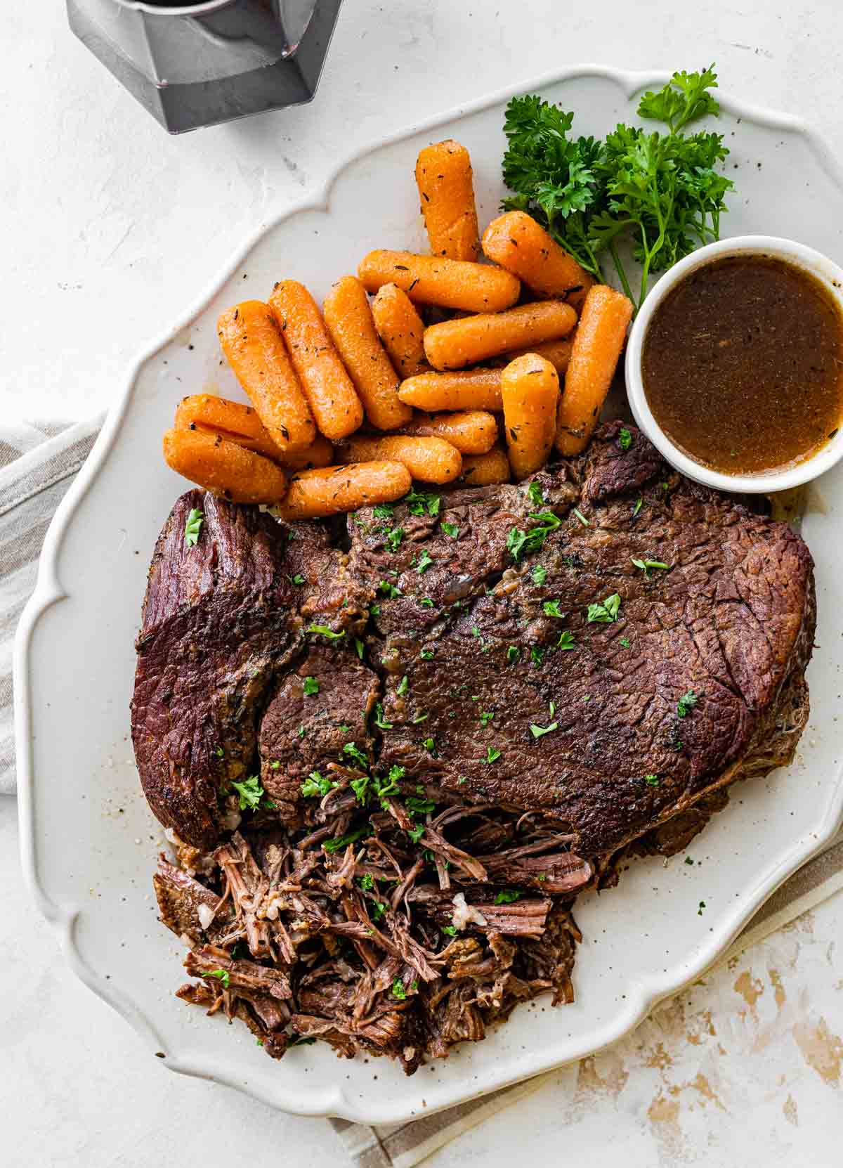 cooked beef roast and carrots on a white plate