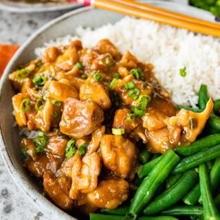 Slow Cooker Orange Chicken plated with rice and green beans with chopsticks on plate, 1x1