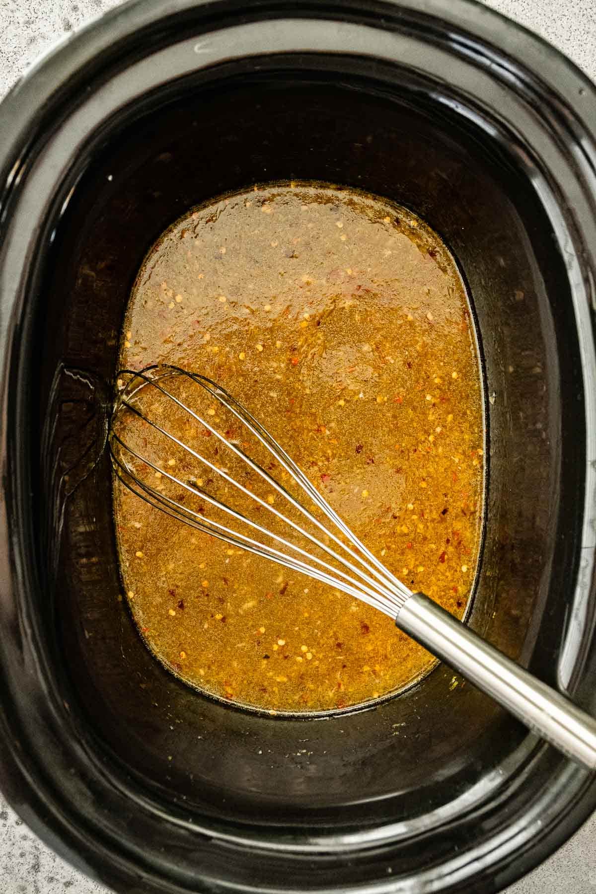 Slow Cooker Orange Chicken whisking sauce ingredients in slow cooker