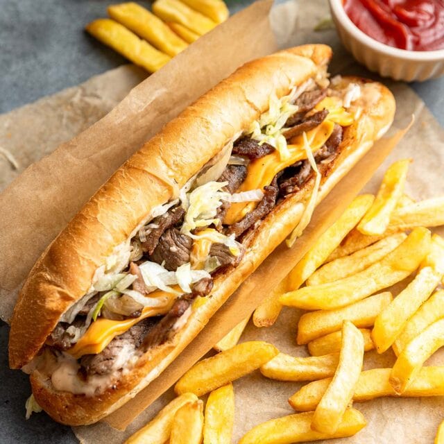 Full picture of the finished Big Mac Philly Cheesesteak with French fries and ketchup.