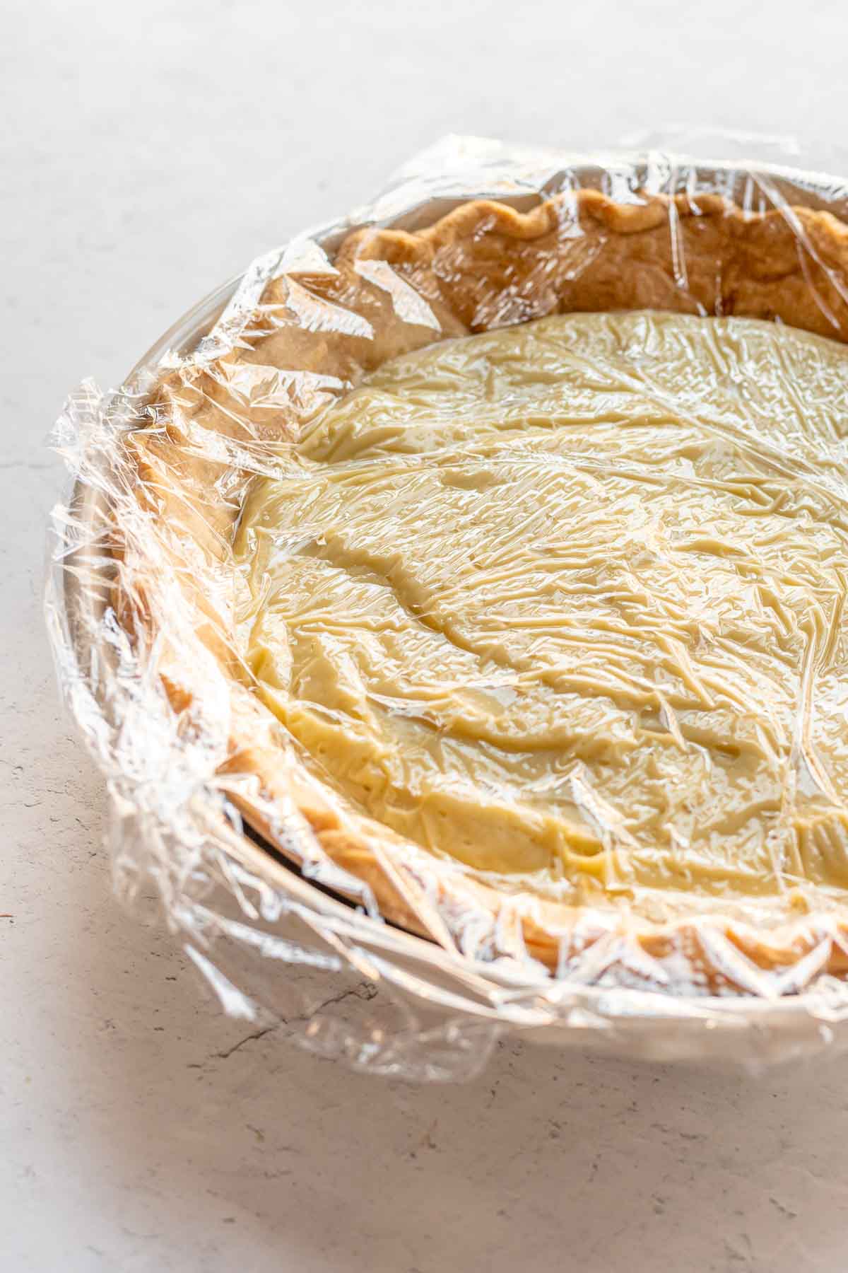 cream pie covered with plastic wrap for cooling