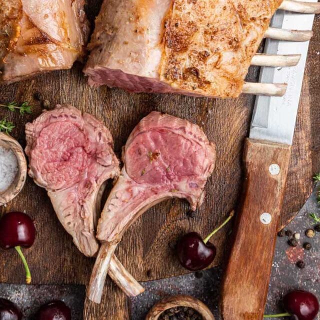 Slices of roasted lamb on cutting board with knife.