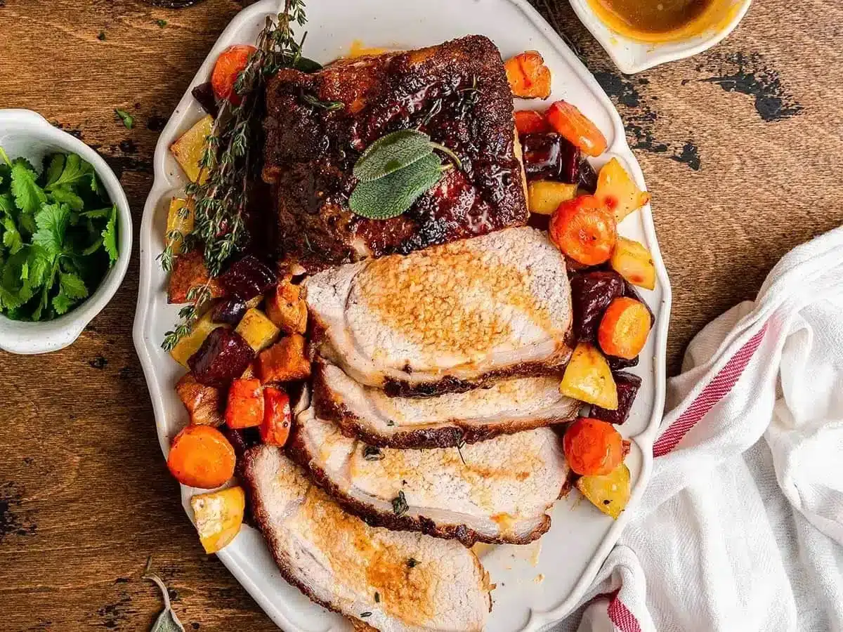 sliced pork with gravy and veggies and garnish on plate