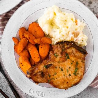 pork on a plate with carrots and mashed potatoes