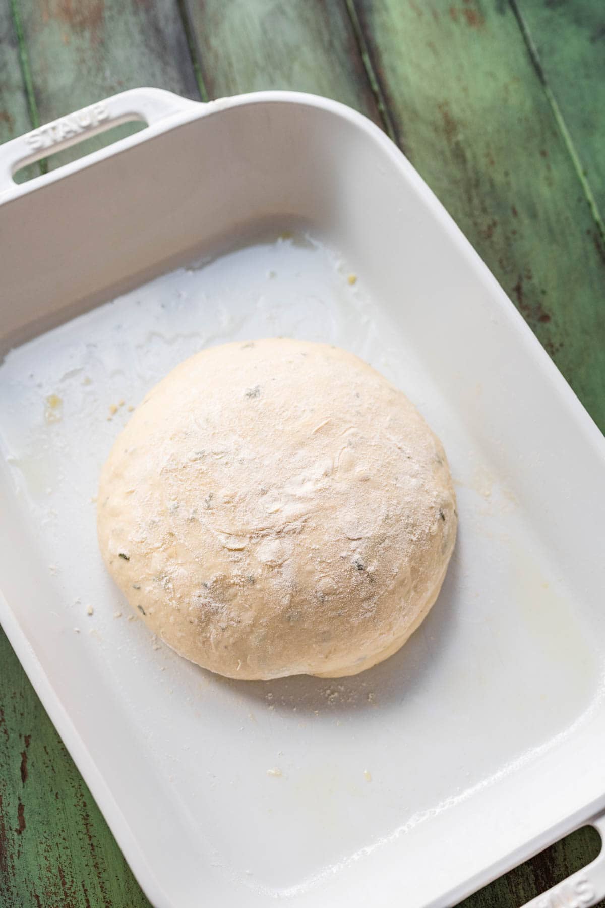 Crusty Garlic Herb Bread dough after proofing, shaped as round in baking dish