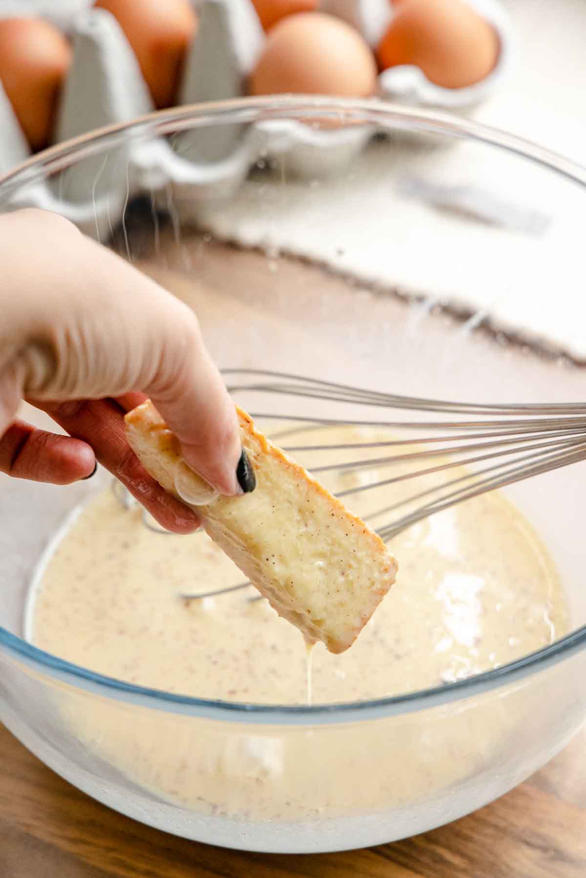 French Toast Sticks dipping bread sticks in egg batter with whisk in bowl