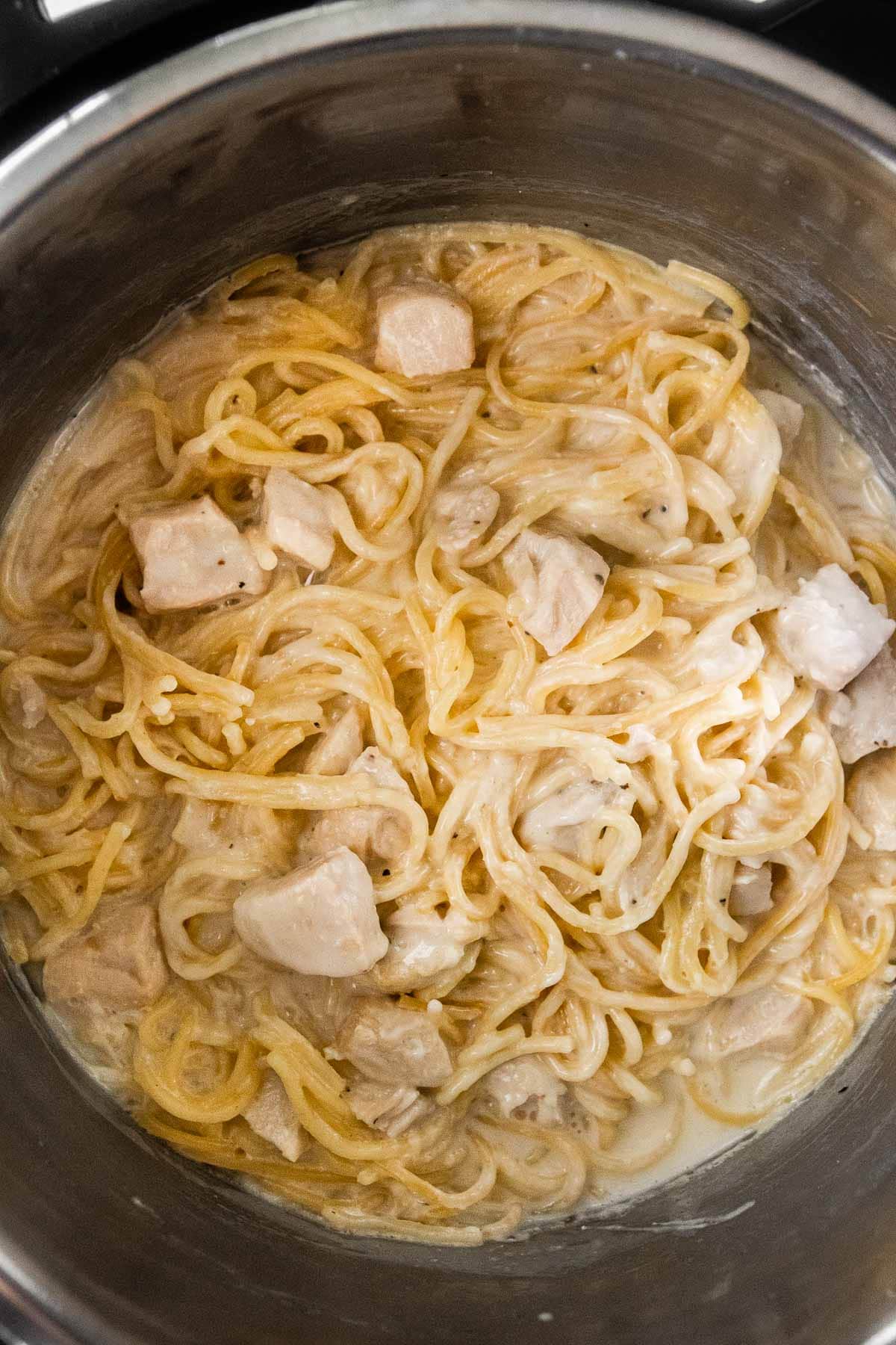 Instant Pot Chicken Alfredo cooked pasta and chicken in pot after adding sauce