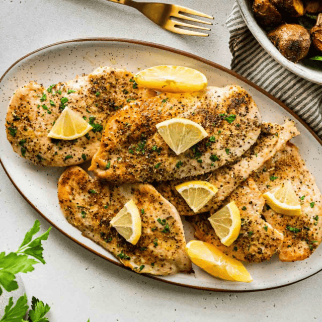 chicken on a plate with lemon slices on top