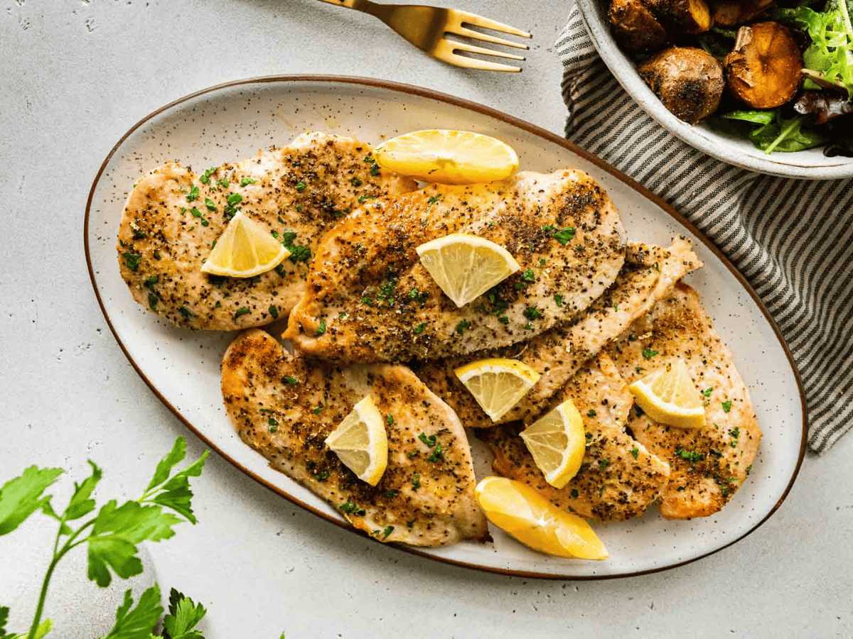 chicken on a plate with lemon slices on top