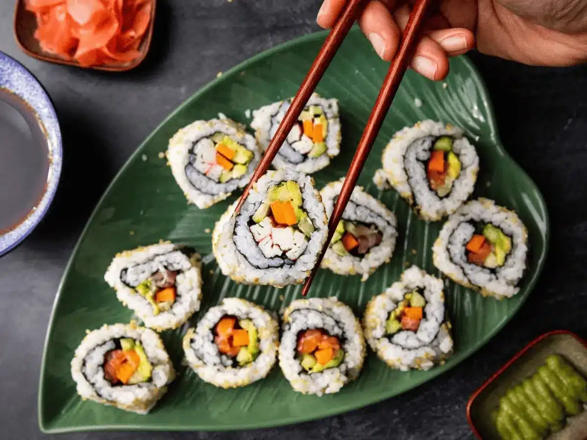 a piece of sushi roll being picked up by a pair of chopsticks