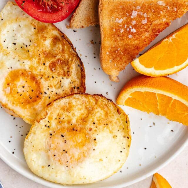 Plate with fried egg, toast, and tomato slice.