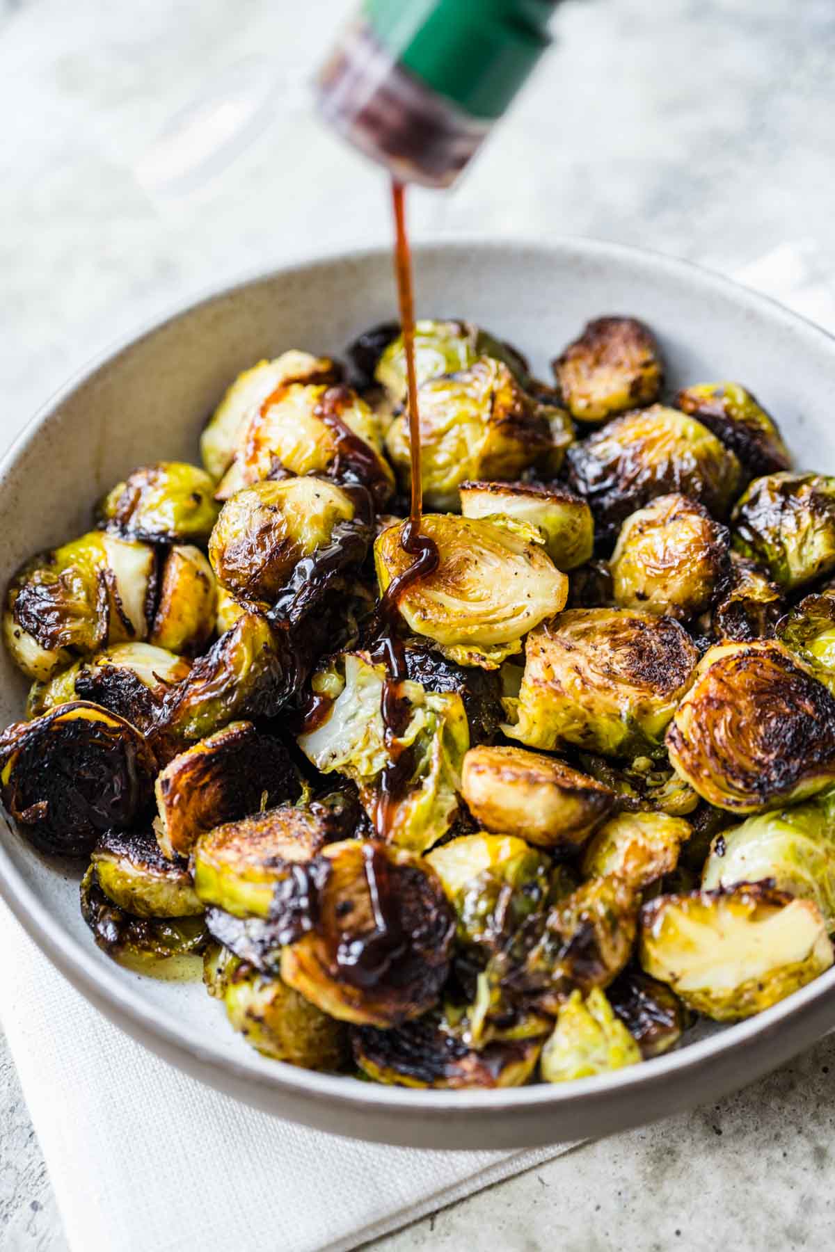 Finished Roasted Balsamic Brussels Sprouts being drizzled with glaze