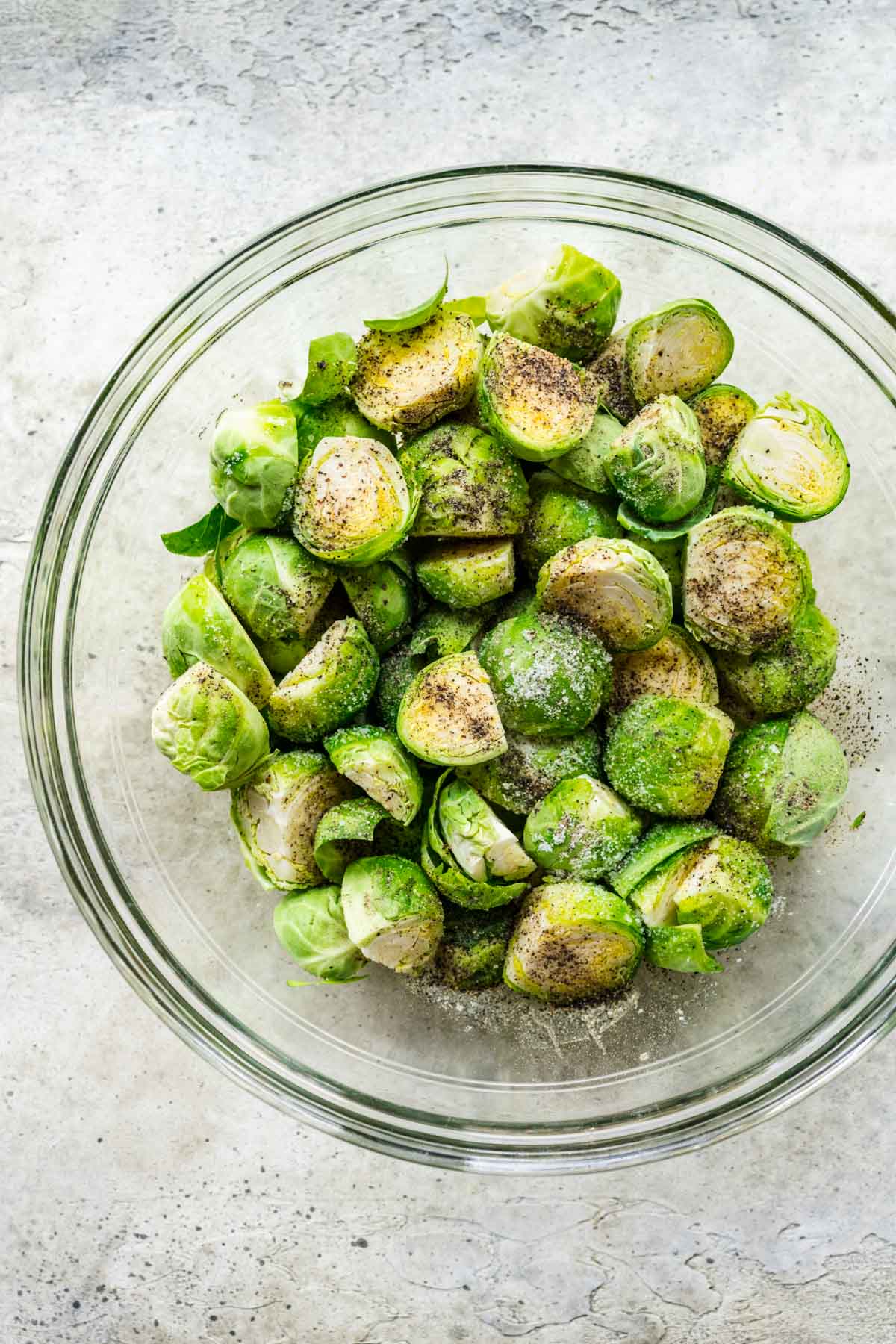 Roasted Balsamic Brussels Sprouts being tossed in oil and seasoning