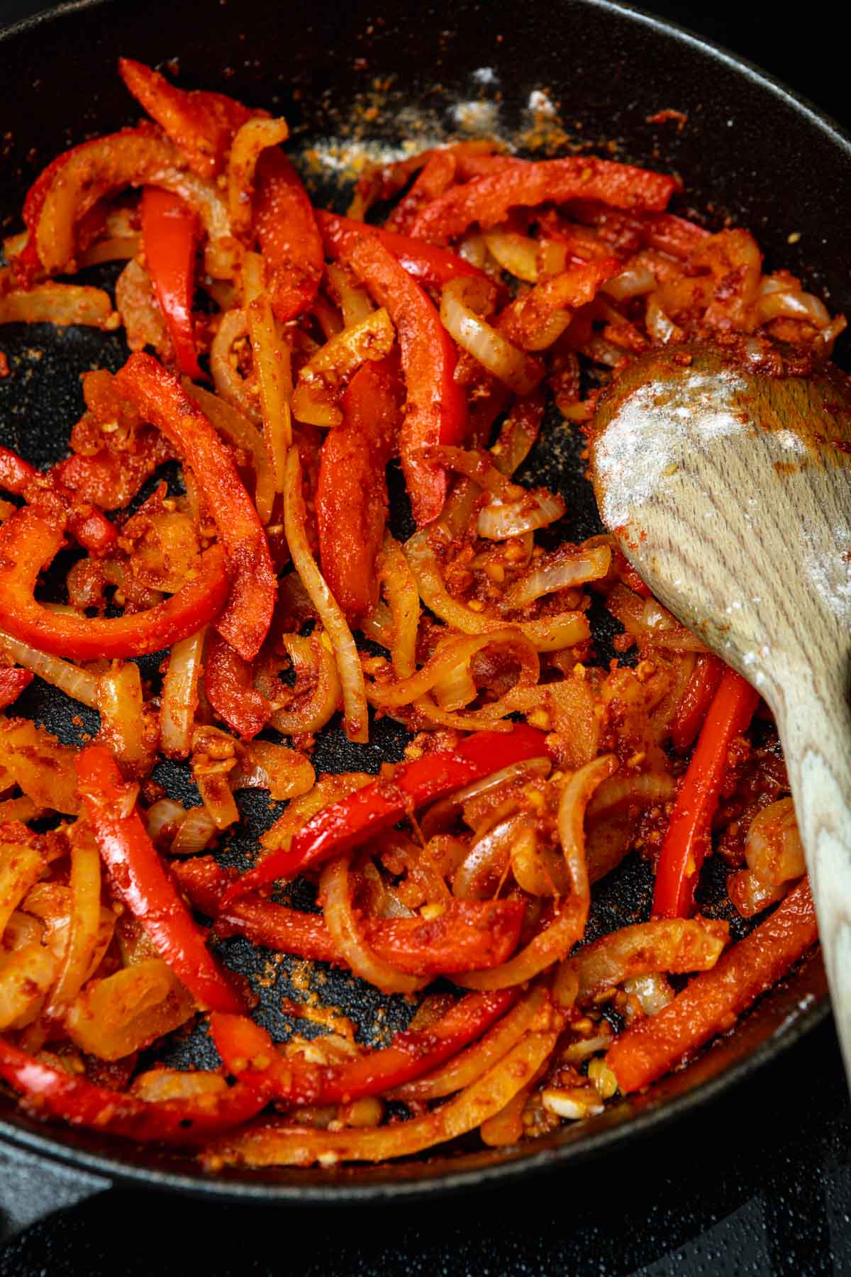 bell peppers and onions with seasoning frying in skillet