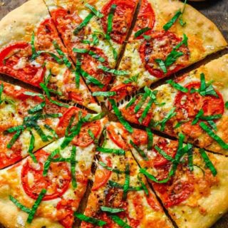 Close up of baked pizza, with tomatoes and basil.