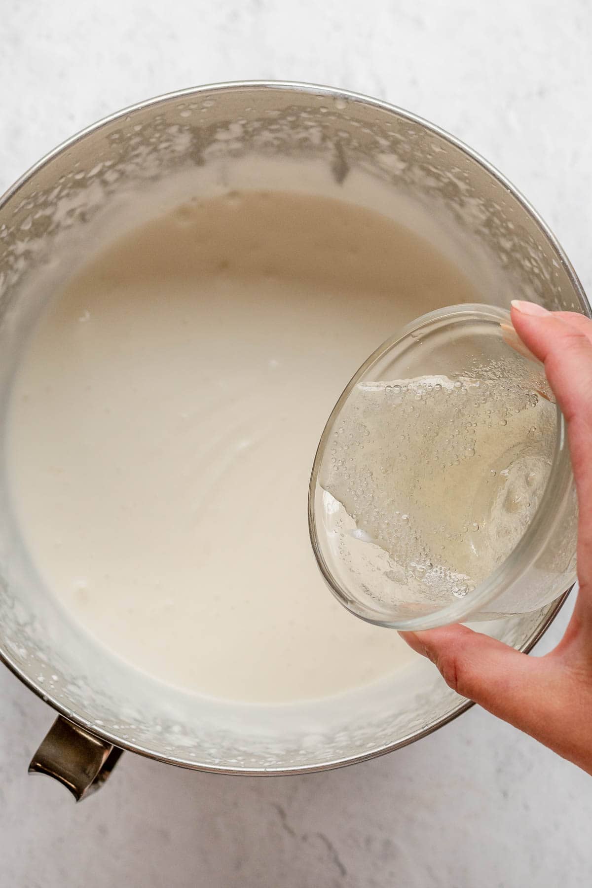Coconut Poke Cake adding gelatin mixture to cream in mixing bowl