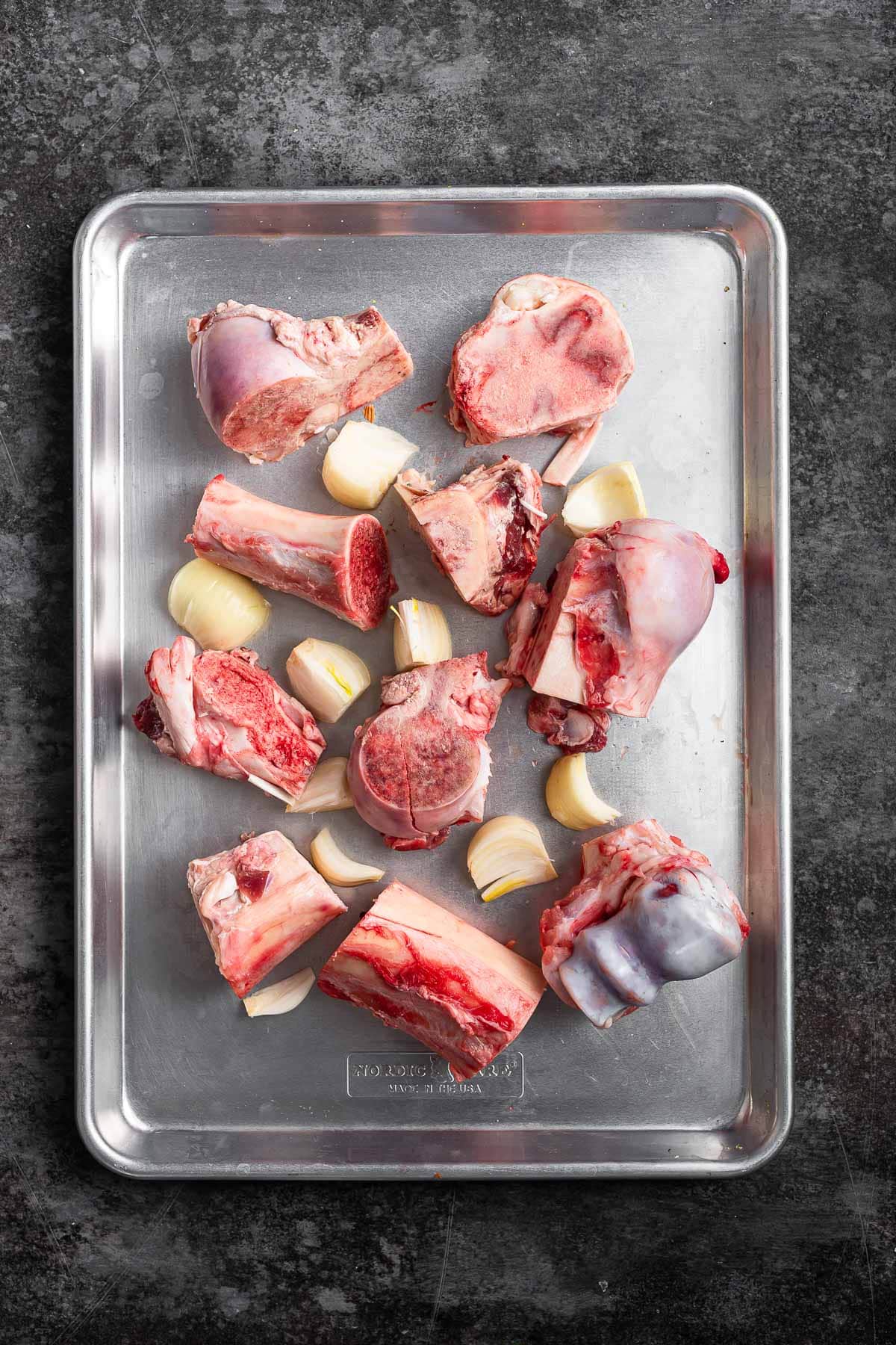 raw beef bones and onions on baking sheet