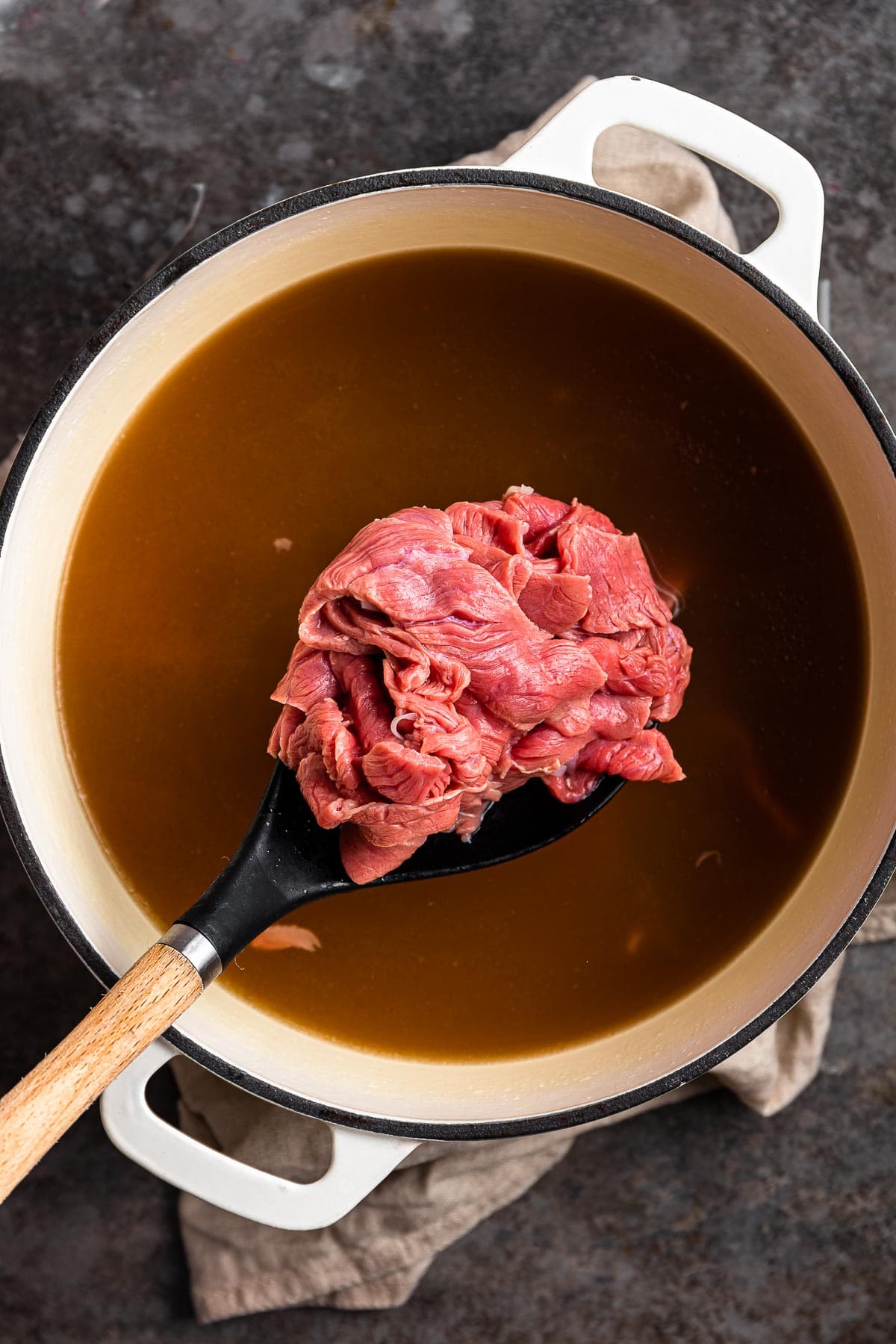adding raw beef to hot broth in Dutch oven