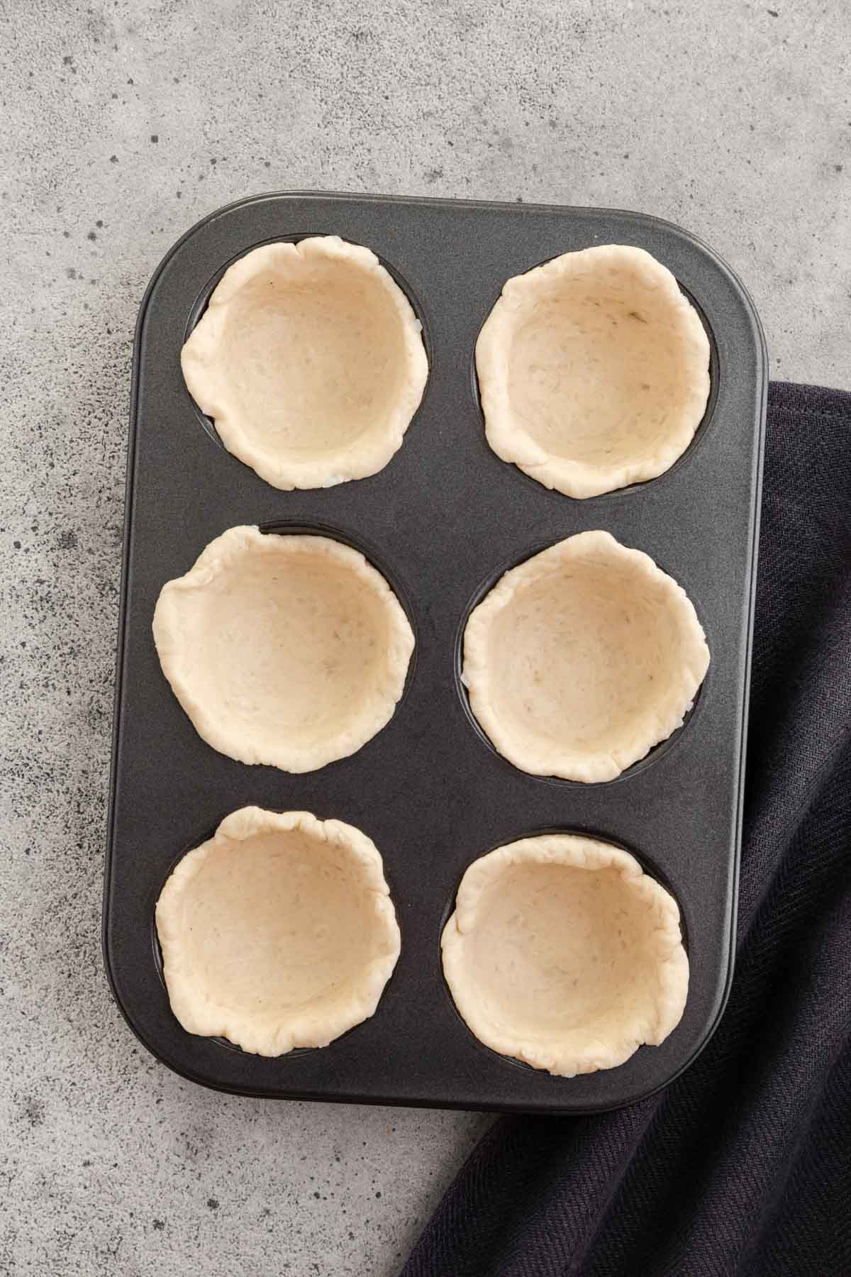 six dough biscuits in a muffin tin