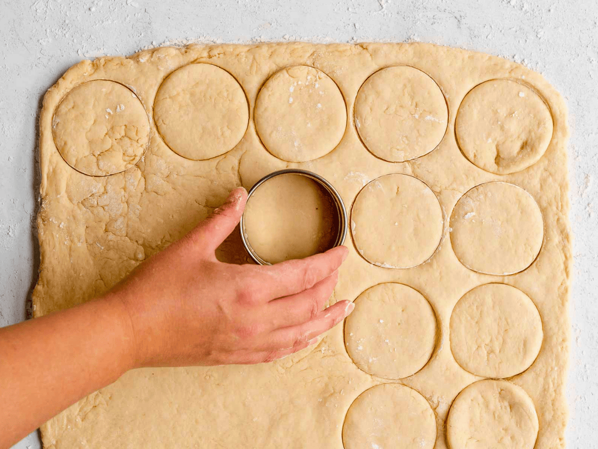 hand using a circular cutter to cut out circle shapes on dough