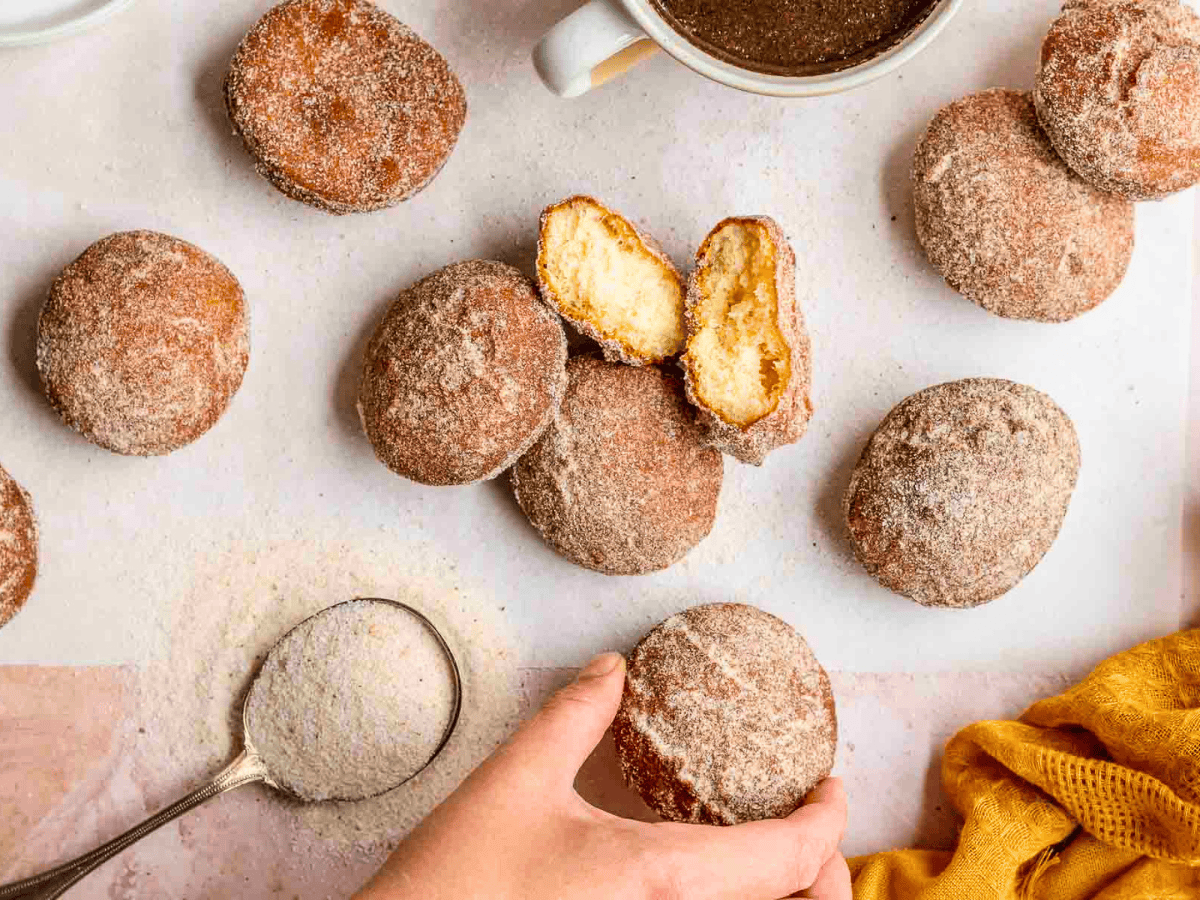 sugar coated circular dough treats on counter with one ripped in half top view