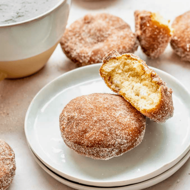 two circle sugar dough treats on a white plate with one bitten in half